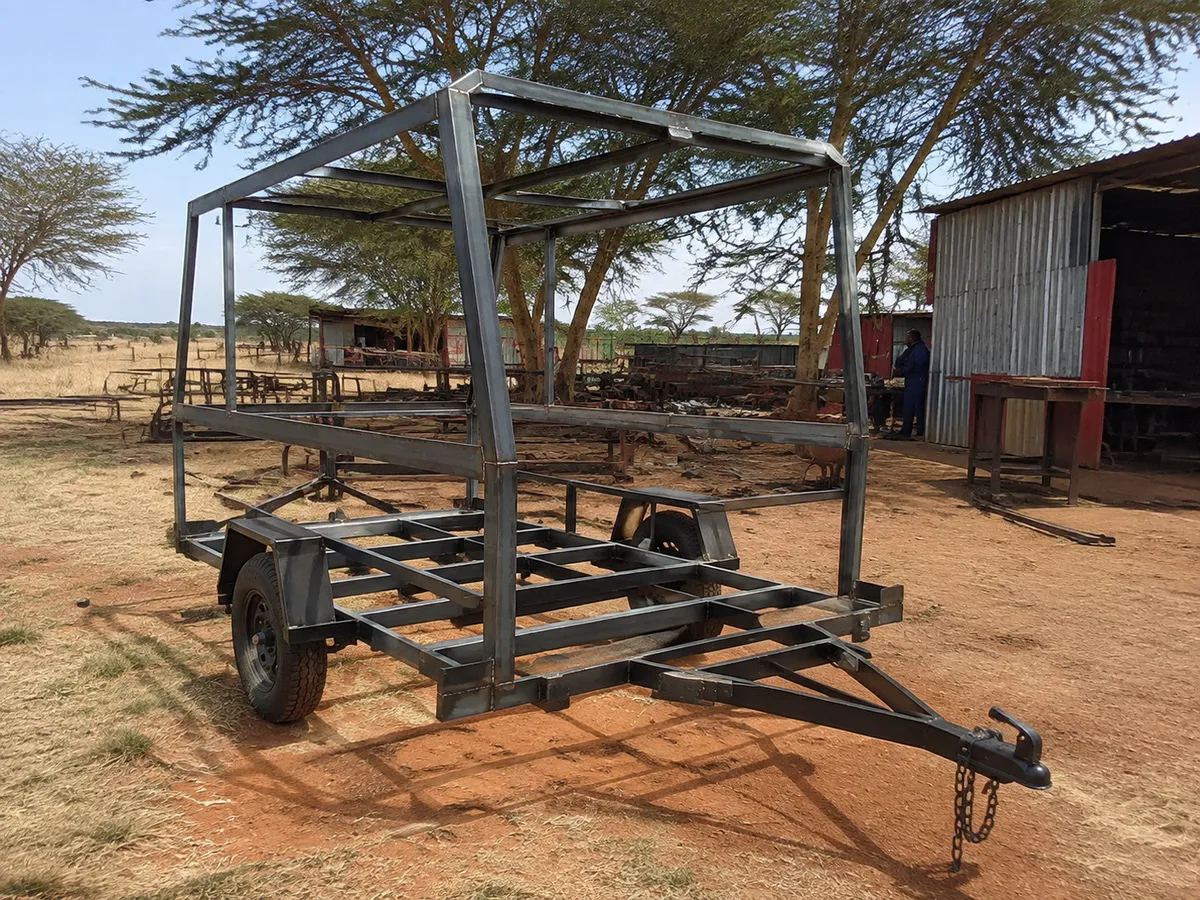 Single-axle trailer with a tall steel canopy frame under fabrication