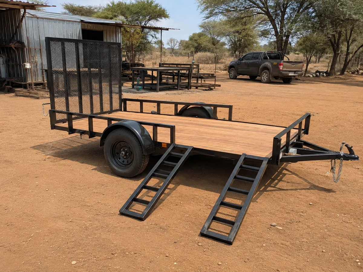 Finished single-axle utility trailer with timber deck, mesh tailgate and loading ramps